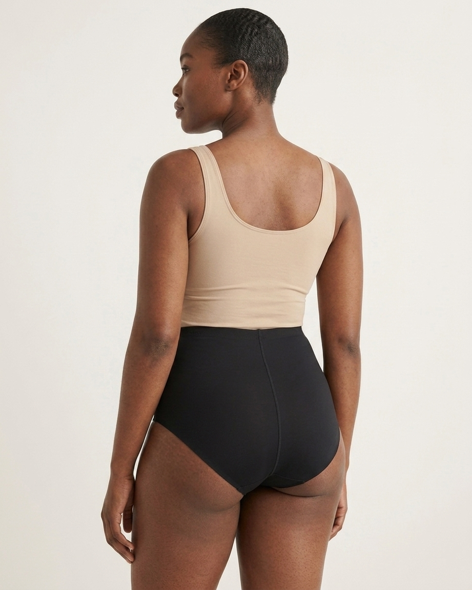 Backside of a woman wearing black Invisible Edge Scalloped Briefs against a plain background
