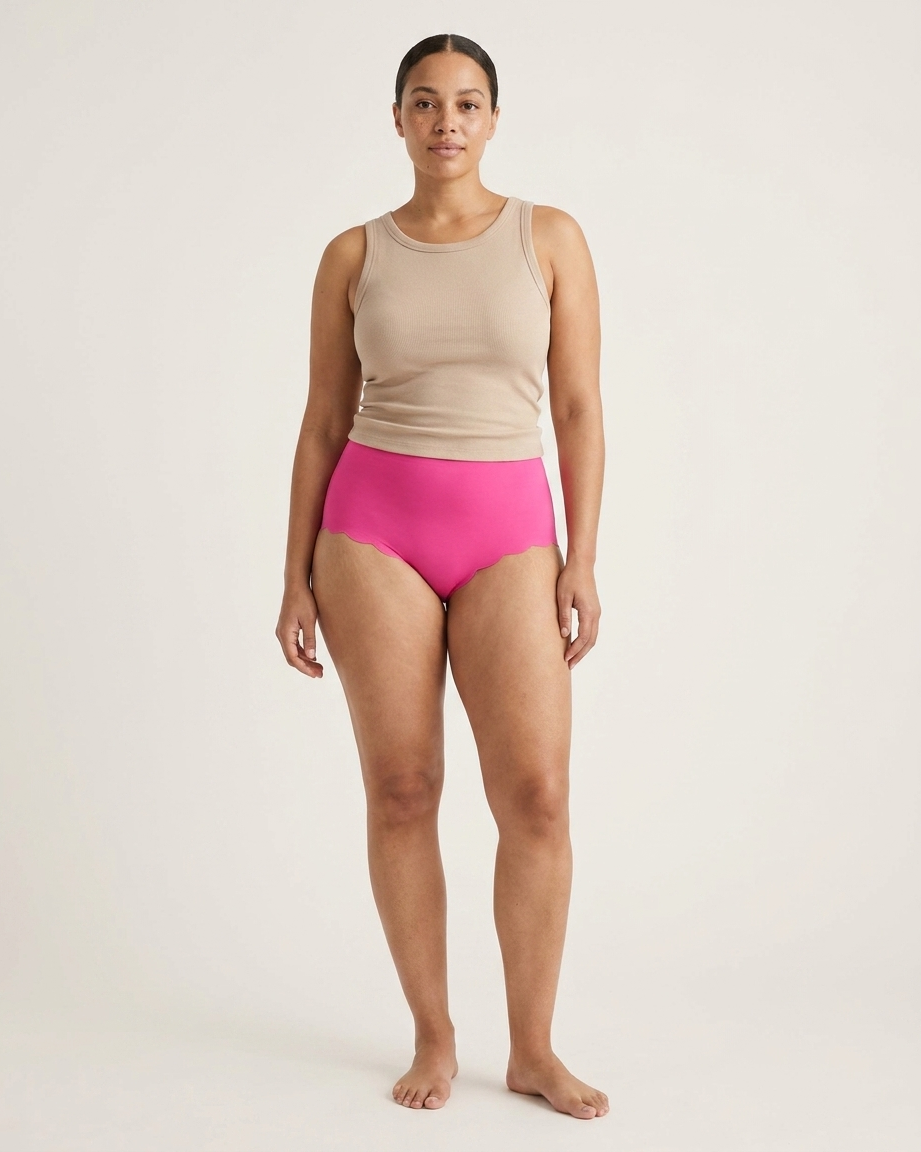 Woman wearing pink Invisible Edge Scalloped Briefs against a plain background