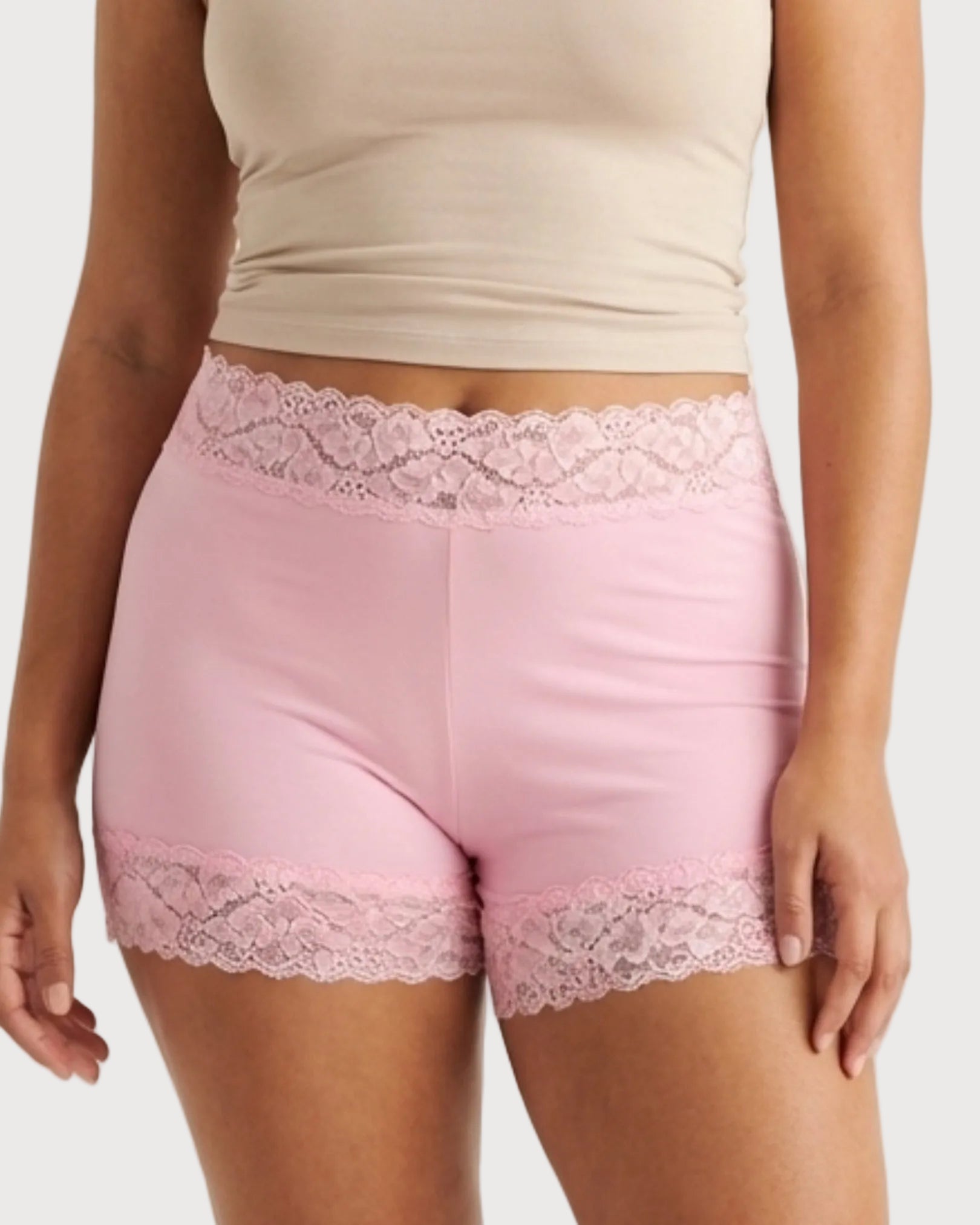 Woman wearing the Seamless Lace Boyshorts in pink on a plain background