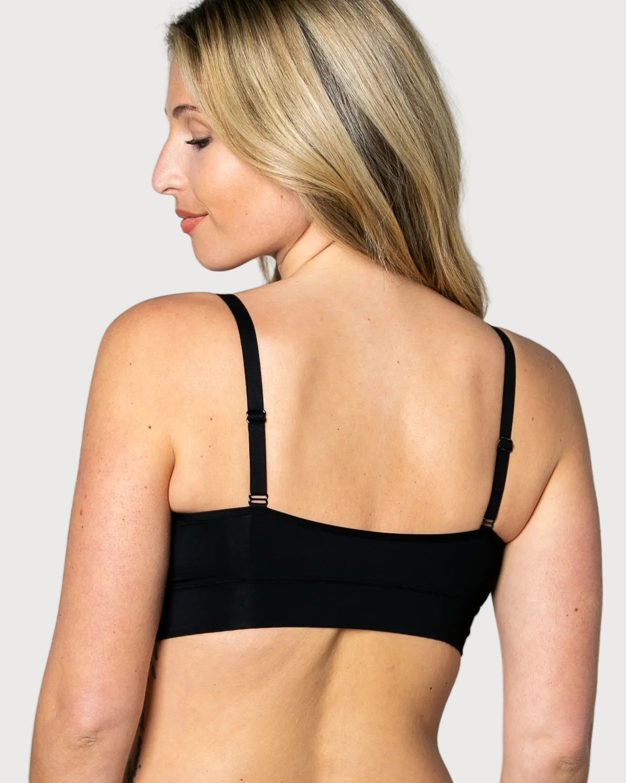 Back view of a woman wearing a black No Wire Underwire bra and panties set against a gray background