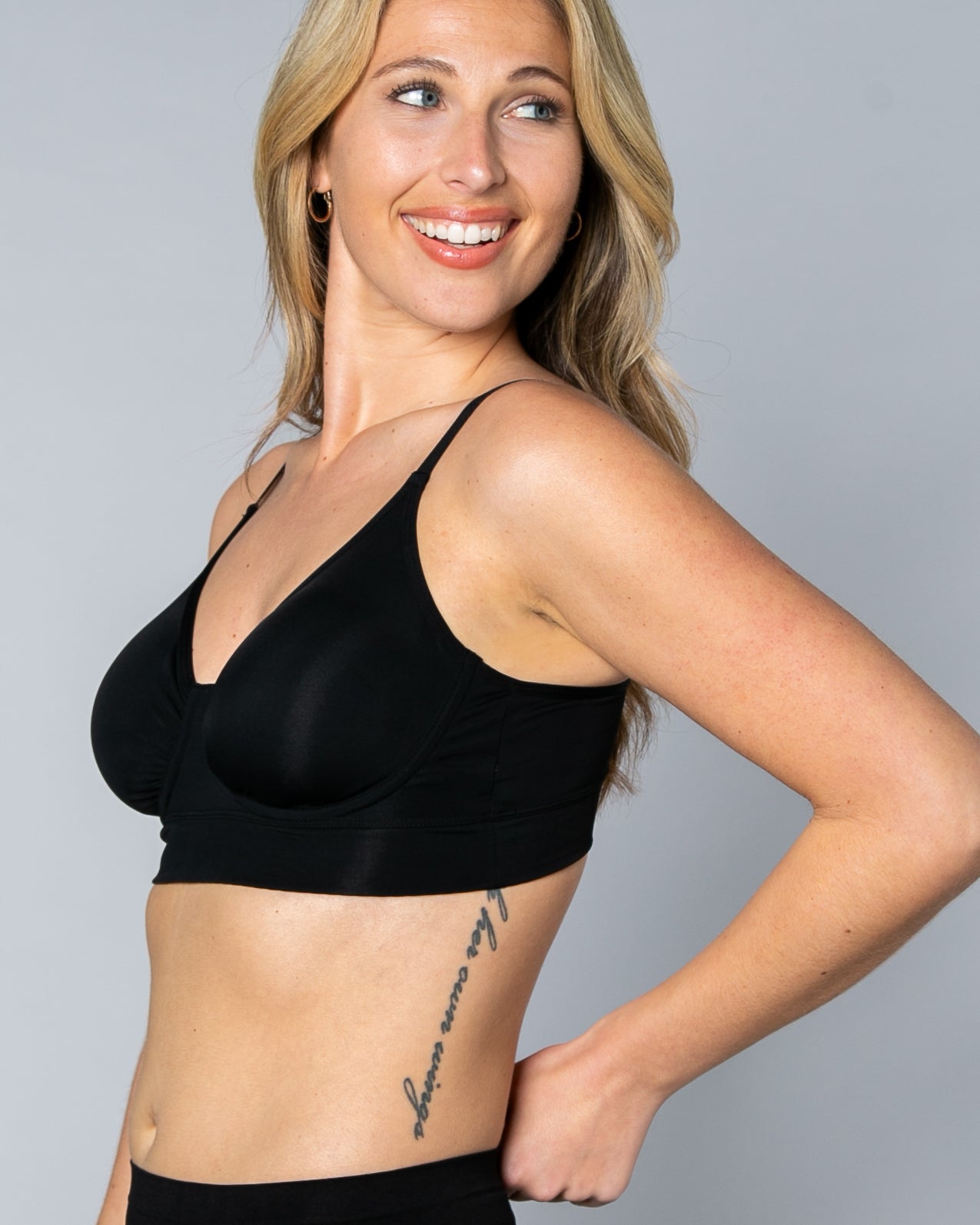 3/4 view of a woman wearing a black No Wire Underwire bra and panties set against a gray background