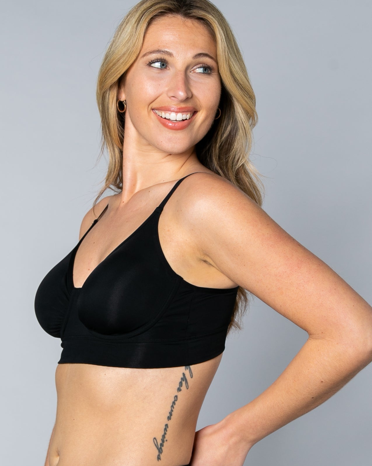 3/4 view of a woman wearing a black No Wire Underwire bra and panties set against a gray background