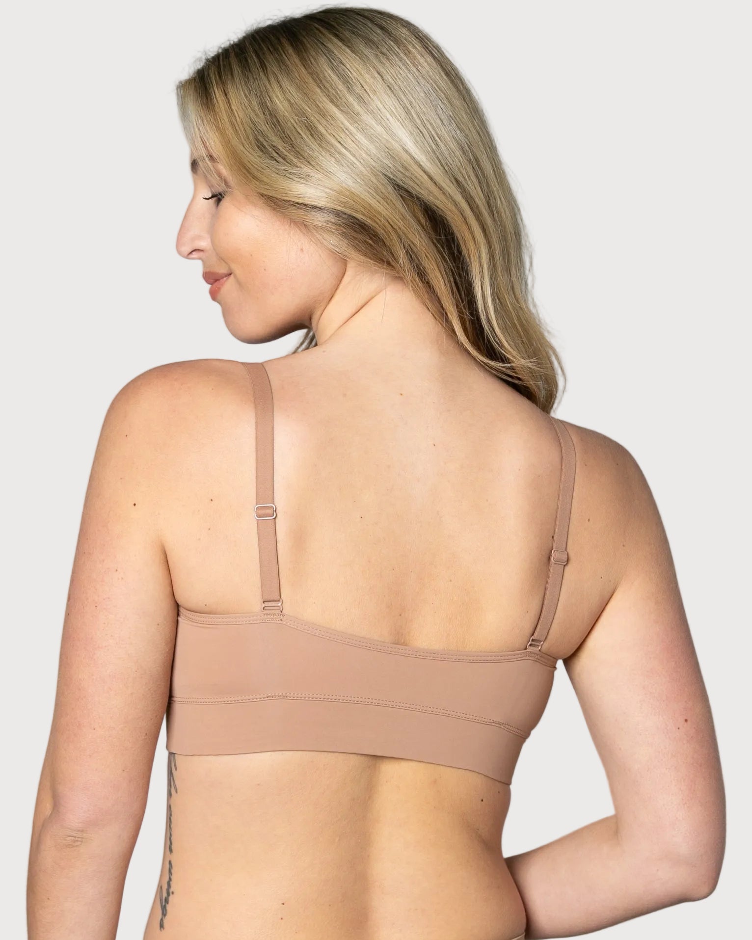 Back view of a woman wearing a beige Butterknit No Wire Underwire bra and underwear set against a gray background