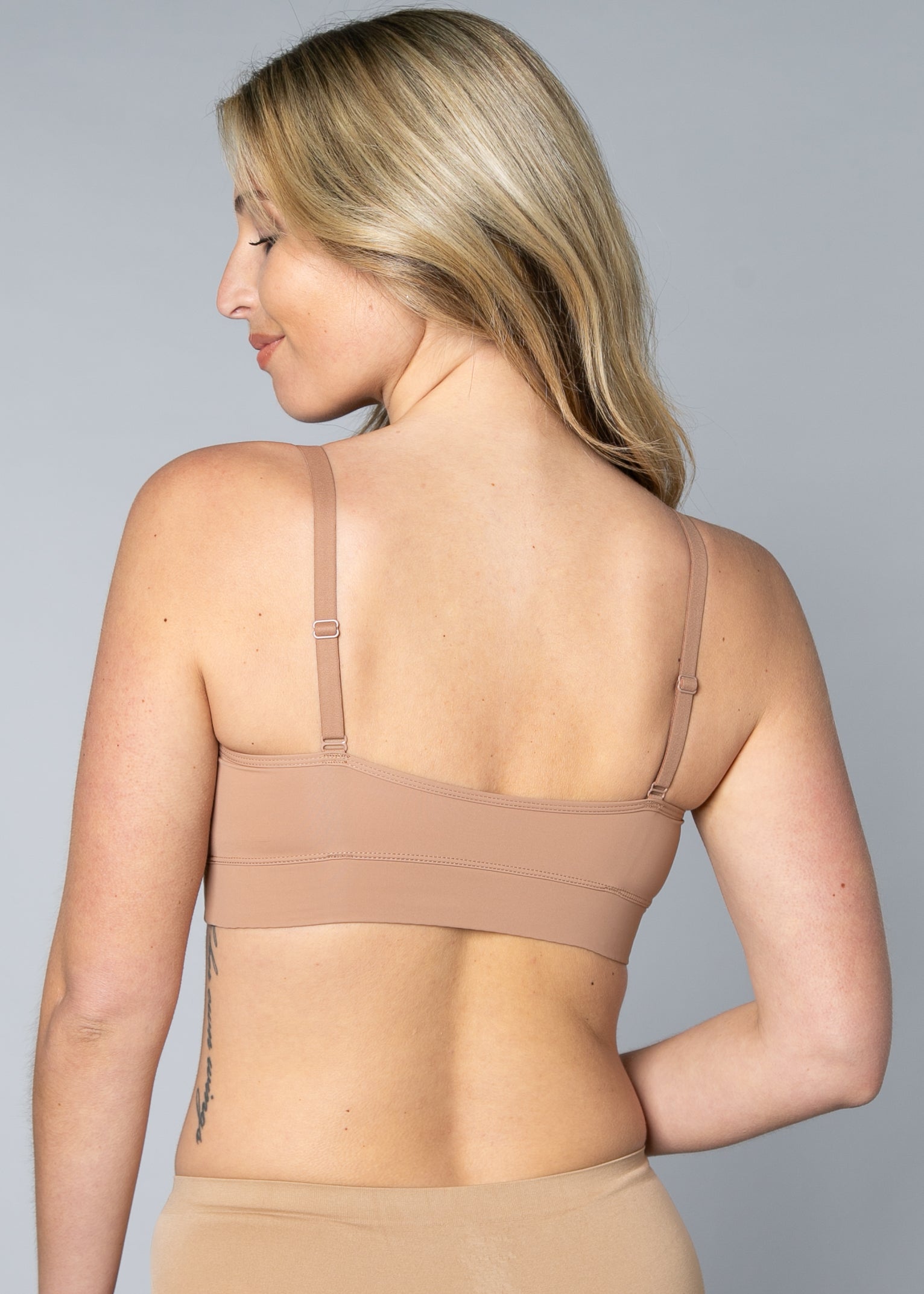 Back view of a woman wearing a beige Butterknit No Wire Underwire bra and underwear set against a gray background