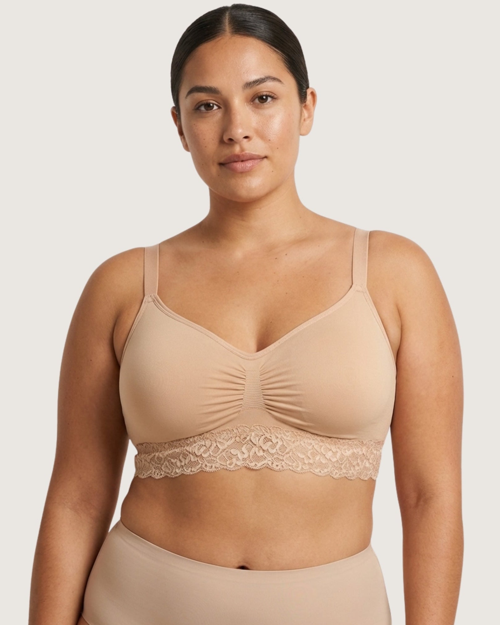 Woman wearing a beige Seamless Bra with lace Band on a plain background