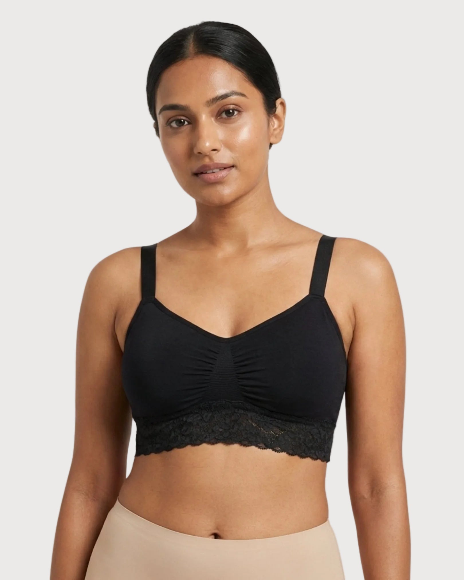Woman wearing a black Seamless Bra with lace Band against a plain background