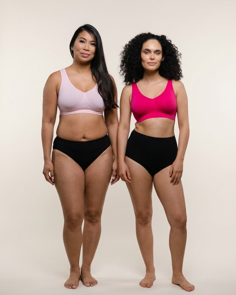 Two women wearing black high-waisted bikini bottoms and colorful sports bras on a beige background