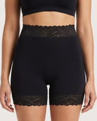 Woman wearing the Seamless Lace Boyshorts in black on a plain background