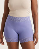 Woman wearing the Seamless Lace Boyshorts in purple on a plain background