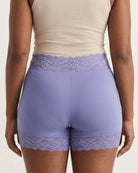 The backside of a woman wearing the Seamless Lace Boyshorts in purple on a plain background