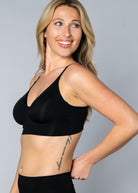 3/4 view of a woman wearing a black No Wire Underwire bra and panties set against a gray background