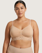 Woman wearing a beige Seamless Bra with lace Band on a plain background