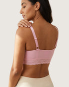 Back view of a woman wearing a pink Seamless Bra with lace Band with lace trim on a plain background