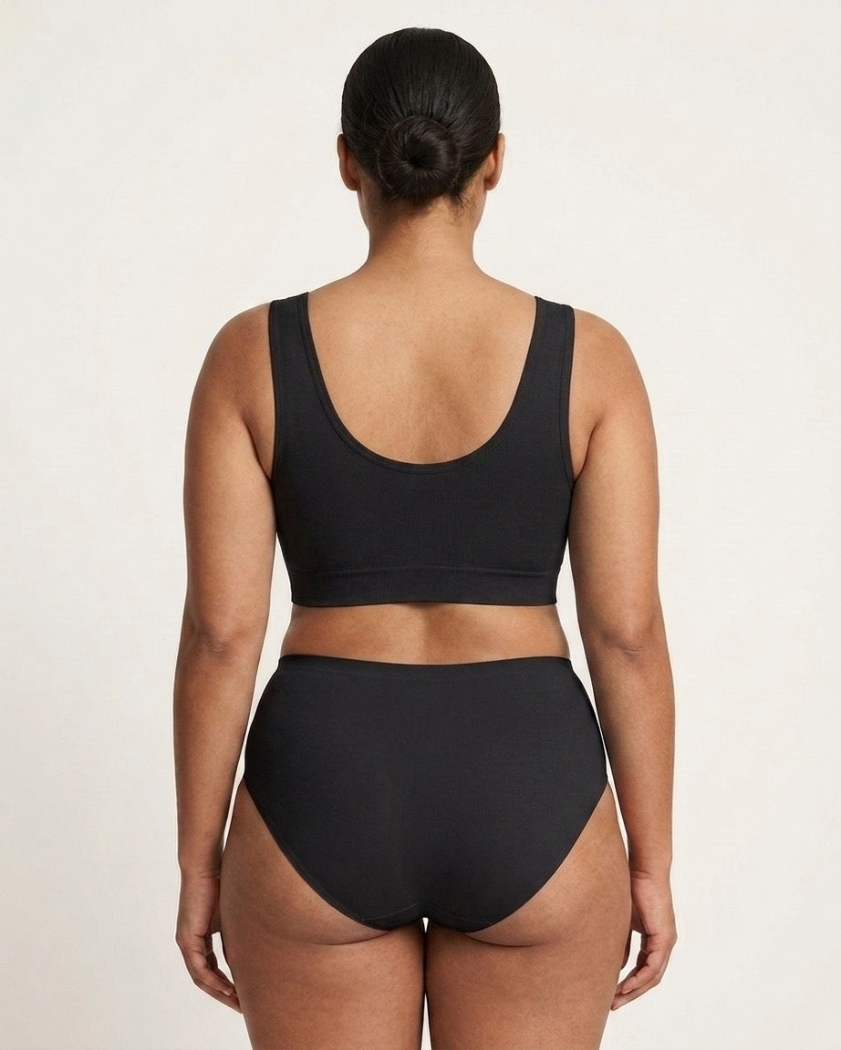 A woman viewed from the back wearing a black Mesh Front Leisure Bra against a plain light background.