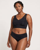 A woman modeling a black Mesh Front Leisure Bra, against a plain light gray studio background.